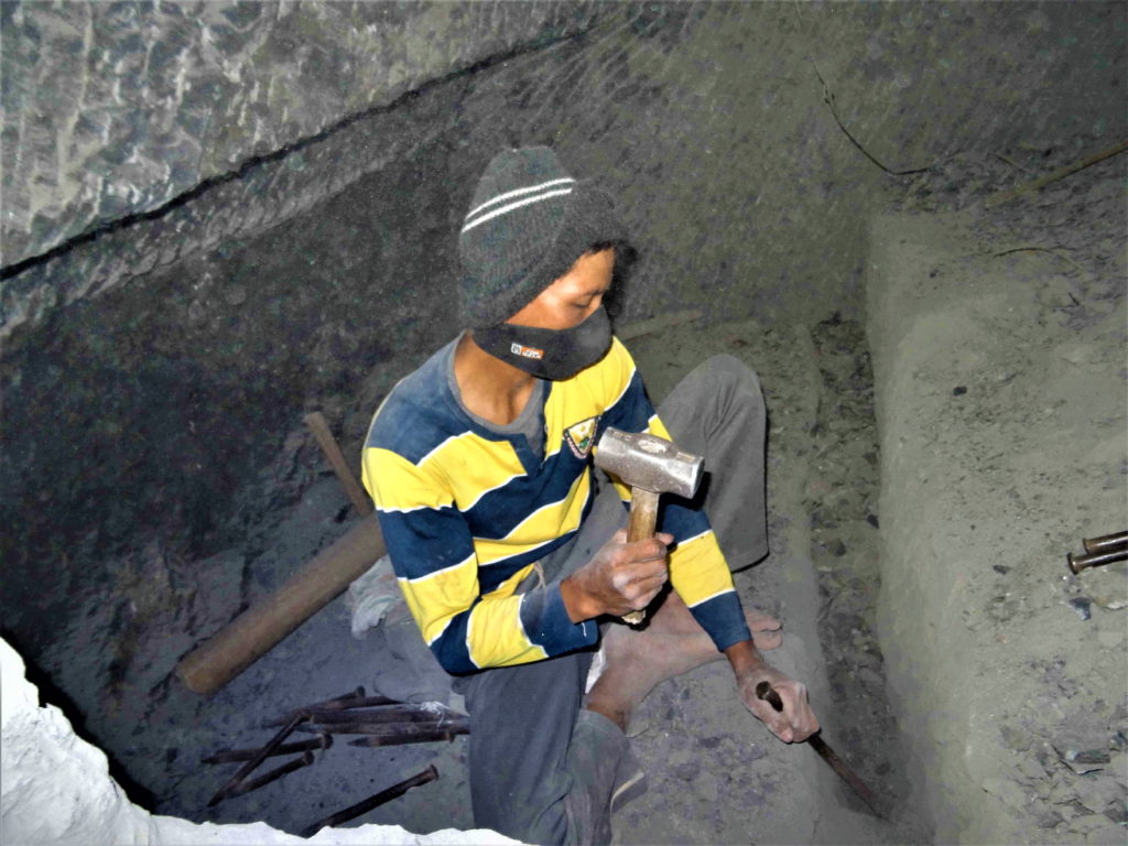 un homme taille au burin et au marteau une Cavité mortuaire à Bori