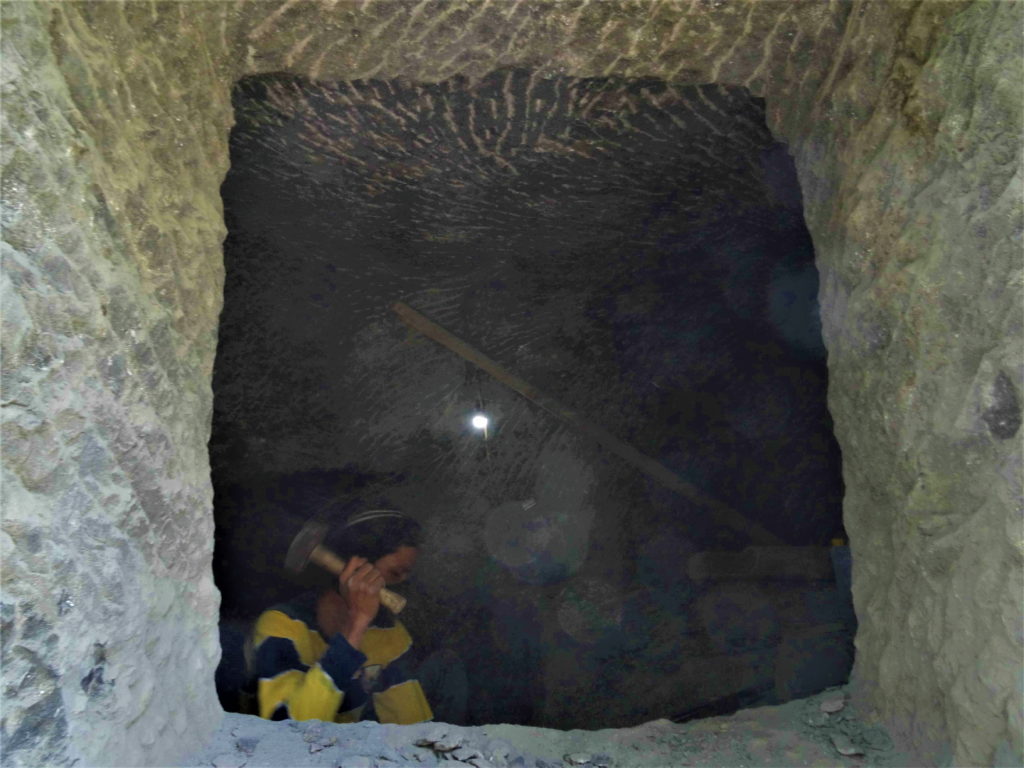 un homme taille au burin et au marteau une Cavité mortuaire à Bori