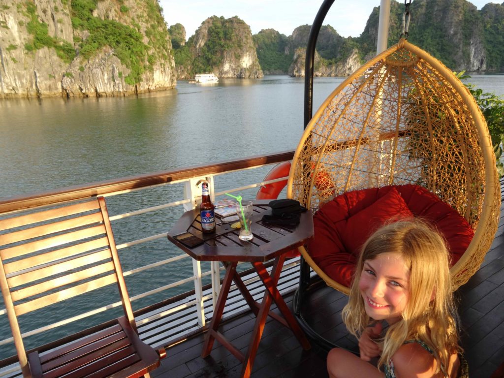 chatounette sur le pont du bateau avec le coucher de soleil sur les pains de sucre de la baie d'halong