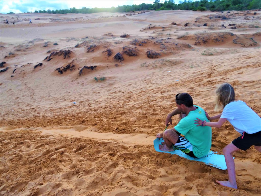 chaton fait de la luge dans les dunes de sables rouges à Mui Ne