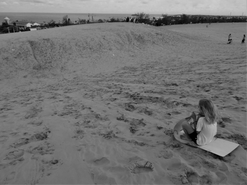 chatounette fait de la luge dans les dunes de sables rouges à Mui Ne