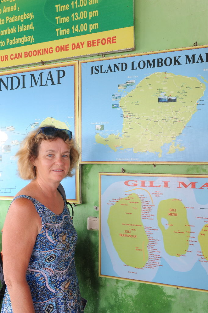 mamisa au guichet pour embarquer aux îles Gili depuis Amed, avec en fond des cartes de Lombok et des îles Gili
