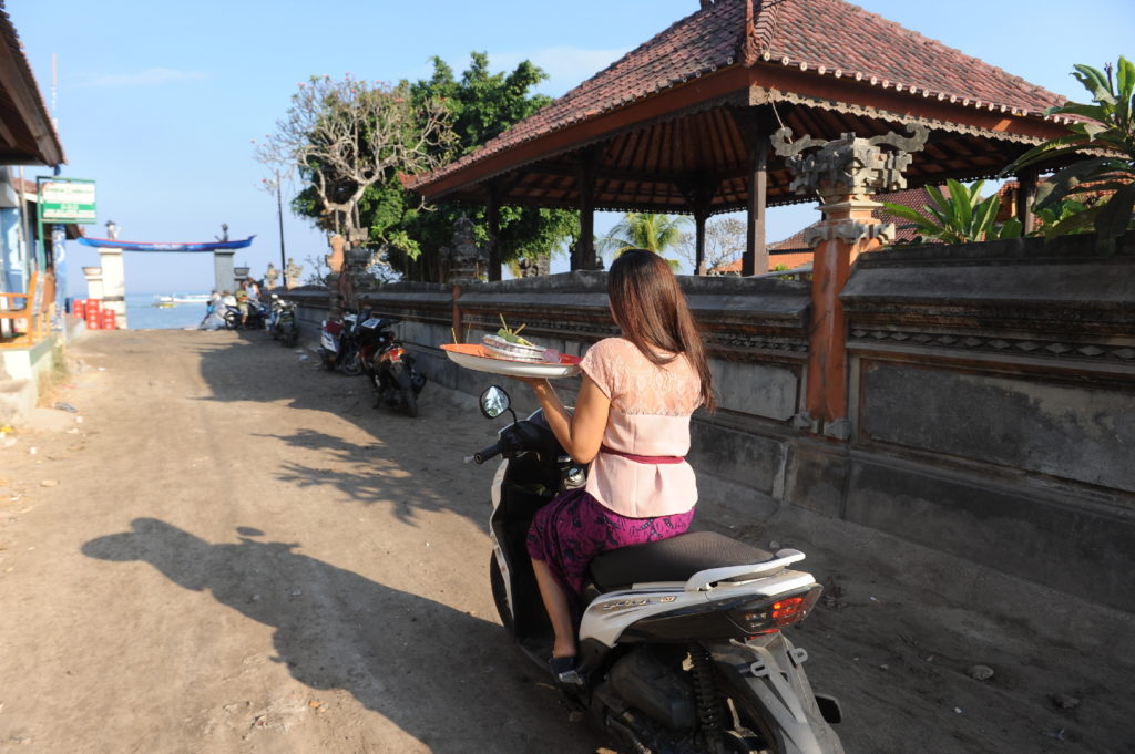 femme à scooter portant un plat dans une main