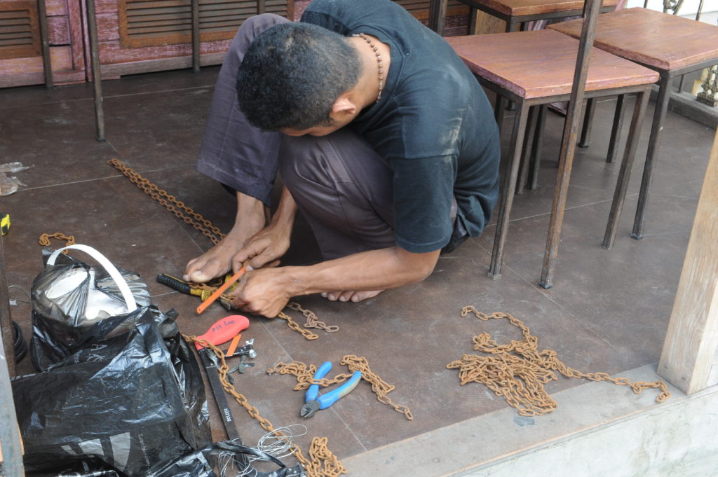 scène de vie dans les rues d'Ubud, homme coupant une chaîne