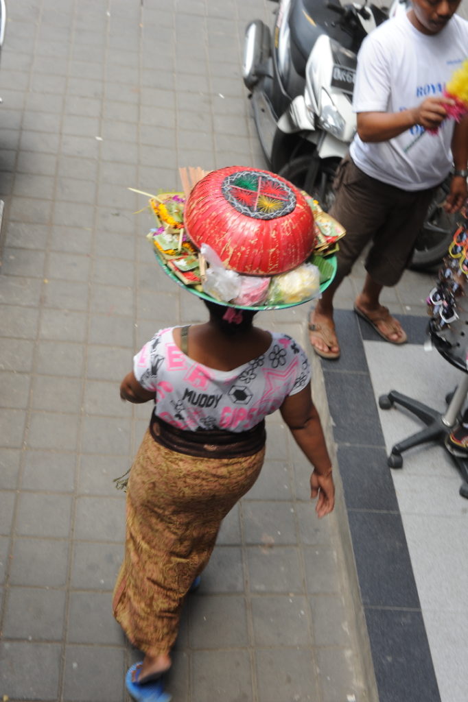 scène de vie dans les rues d'Ubud, femme portant offrandes sur sa tête
