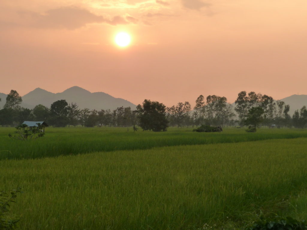coucher de soleil sur les rizières et les montagnes en arrière plan entre chiang rai et phayao, sur une route alternative classée pittoresque par Michelin