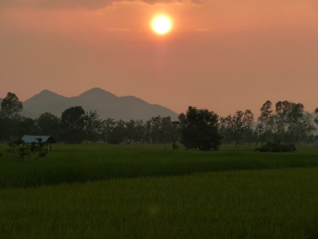 coucher de soleil sur les rizières et les montagnes en arrière plan entre chiang rai et phayao, sur une route alternative classée pittoresque par Michelin