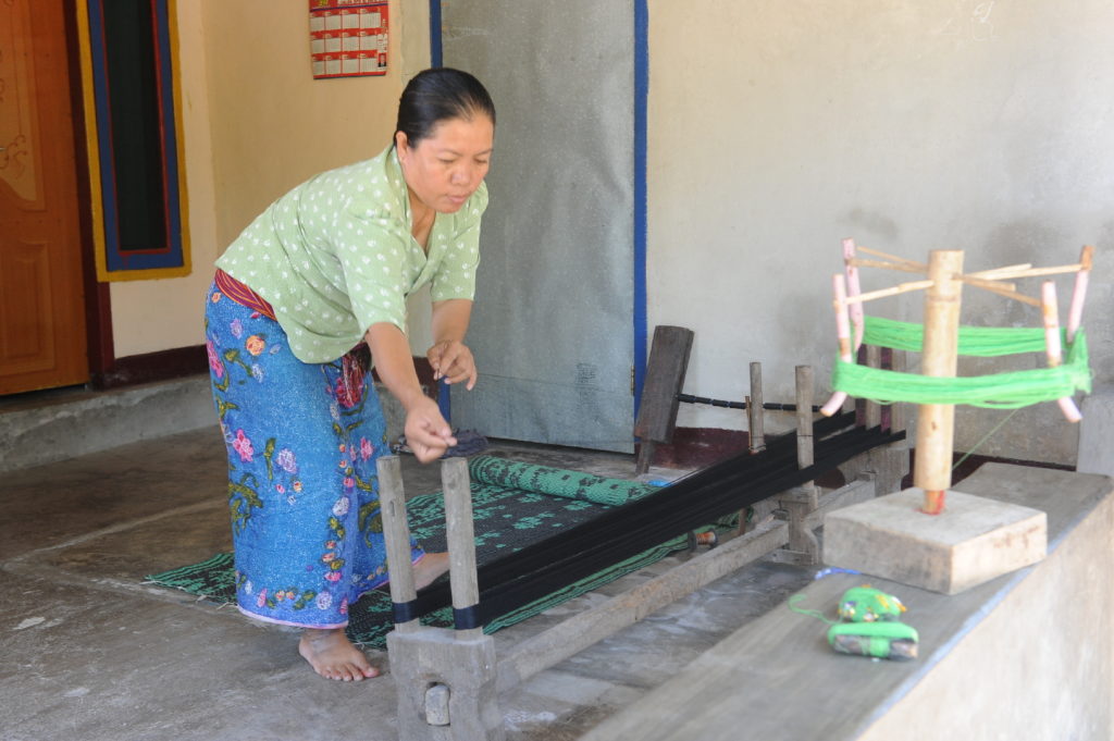 femme travaillant à embobiner le fil pour utiliser sur un métier à tisser à Lombok, boutique à batik