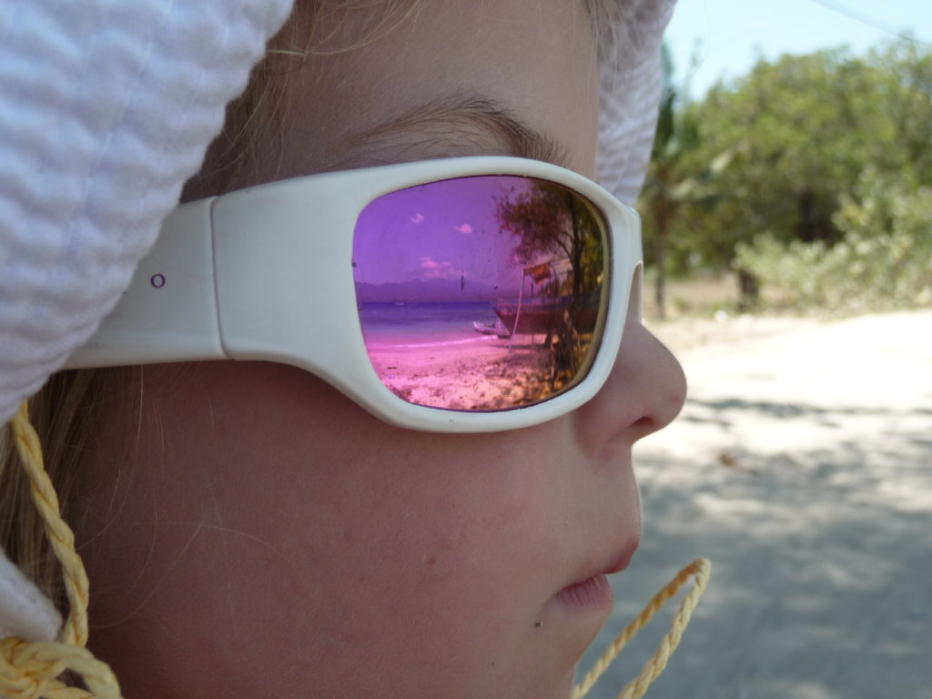 chatounette de profil avec ses lunettes de soleil qui reflètent la plage de gili air