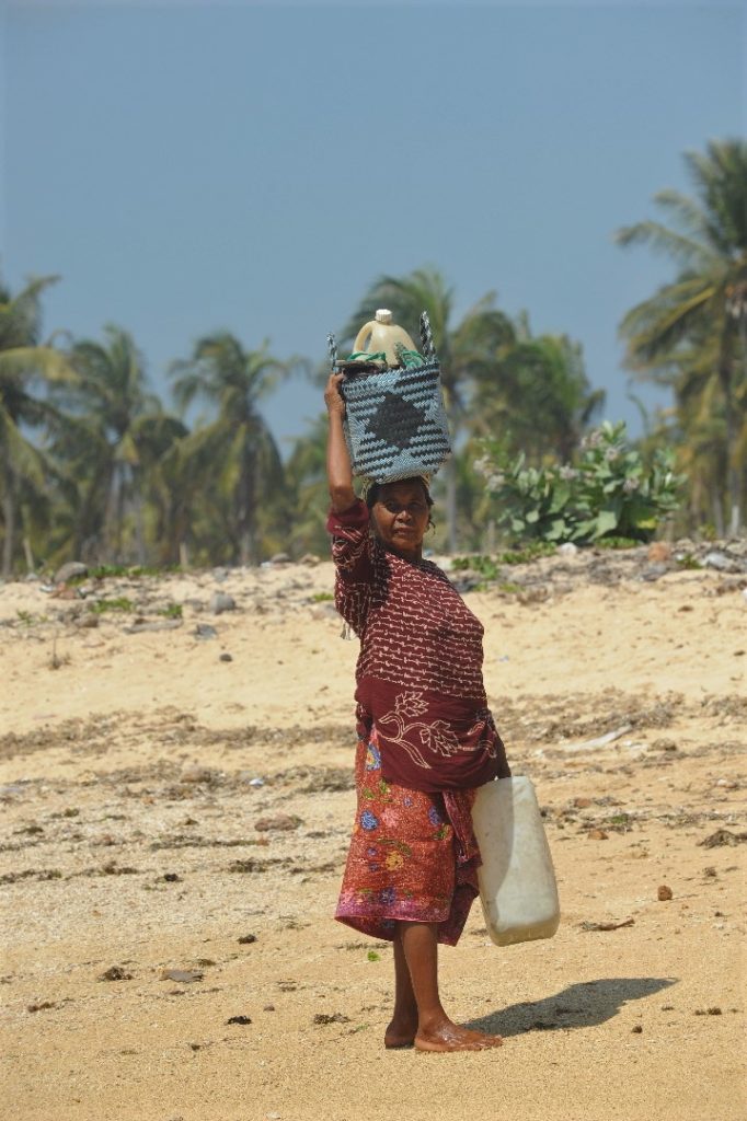 femme portant des objets sur la tête à la plage où ramasser les coquillages entre Kuta Lombok et Tanjung Aan Beach