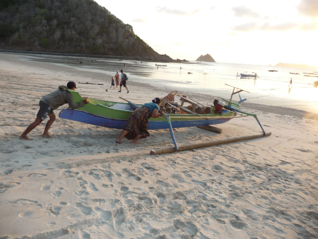 mise à l'eau d'un bateau au coucher de soleil sur la plage paradisiaque de selong belanak, près de kuta lombok