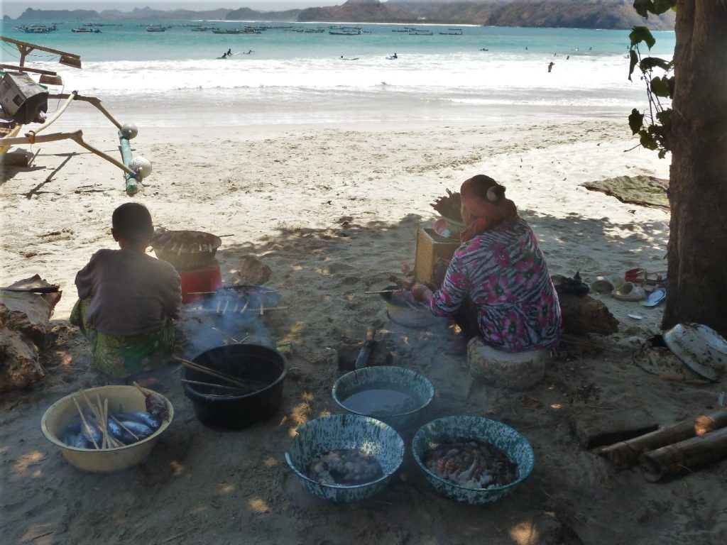 Selong Belanak, plage de rêve de Lombok, au coucher du soleil, femmes faisant griller des brochettes de poissons et calamar