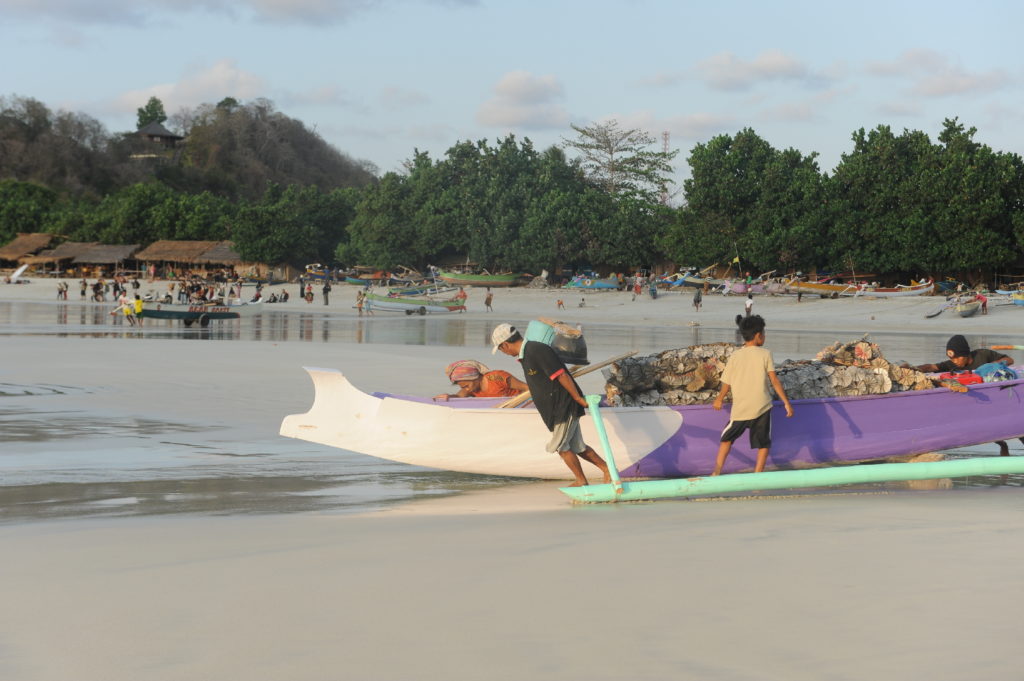 Selong Belanak, plage de rêve de Lombok, au coucher du soleil, pêcheurs mettant le bateau à l'eau