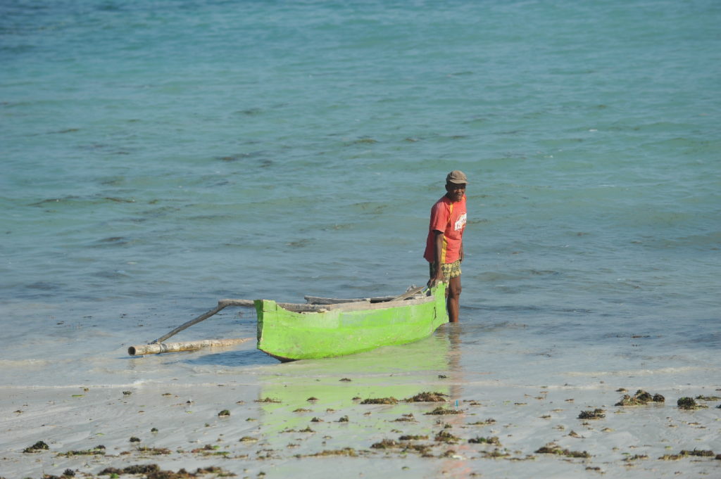 homme mettant son bateau à l'eau depuis la plage de Tanjung Aan Beach
