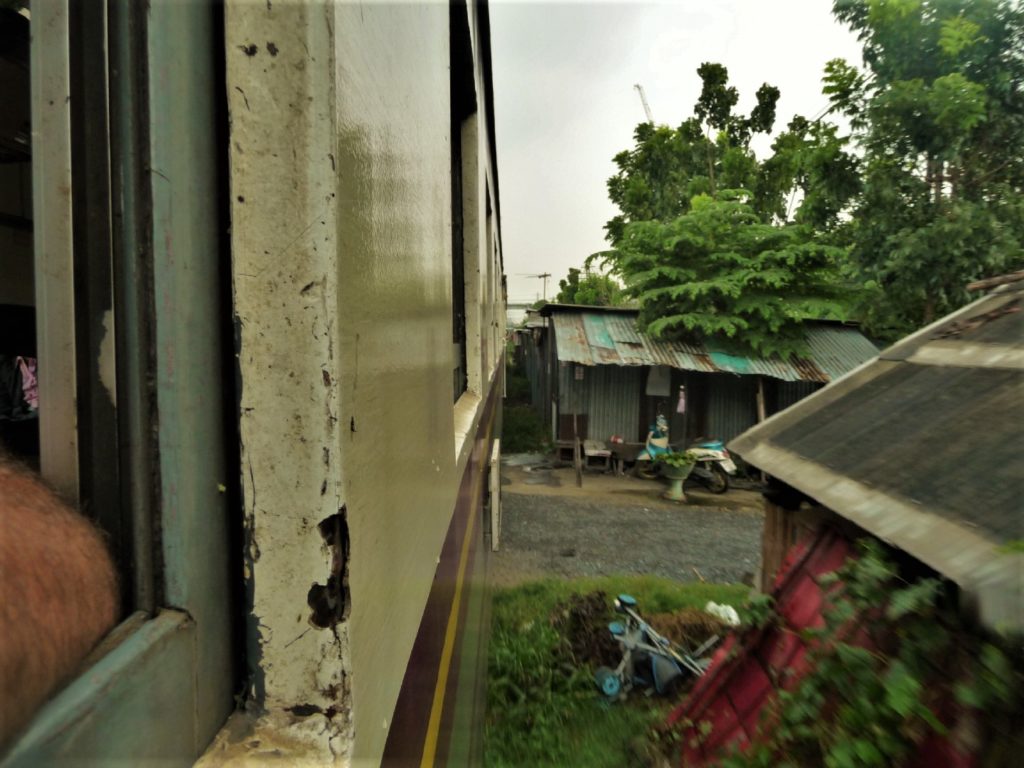 vue depuis notre train entre bangkok et kanchanaburi sur des logements à ras la voie de chemin de fer