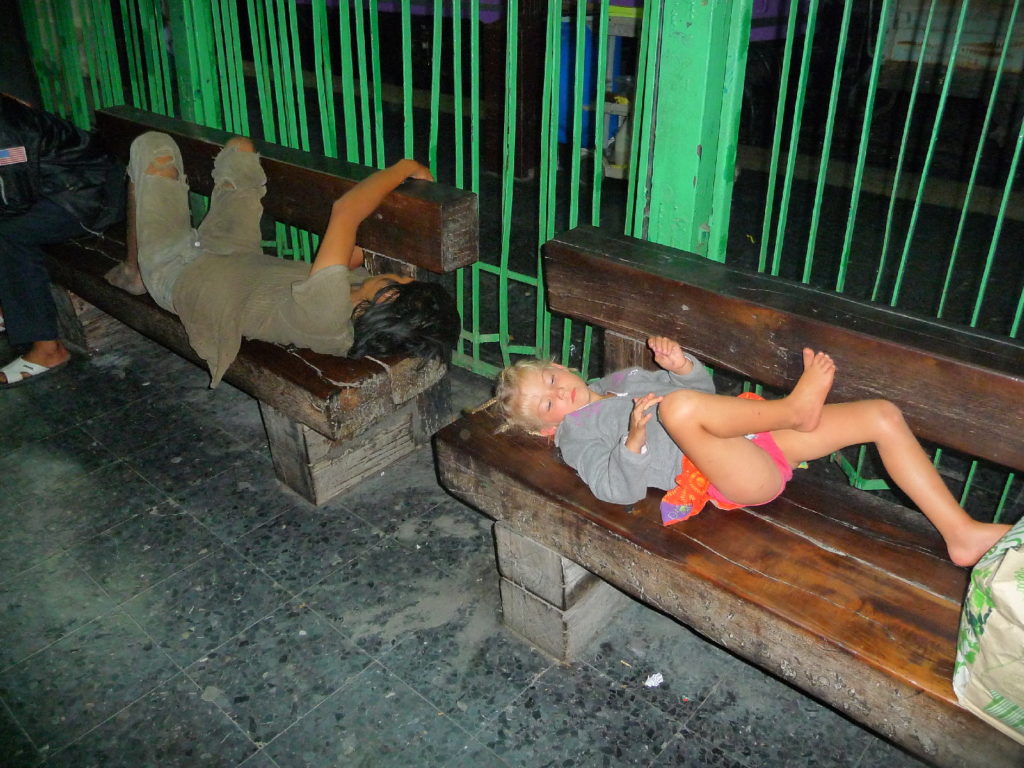 chatounette allongée sur un banc de la gare de bangkok à côté d'un clochard