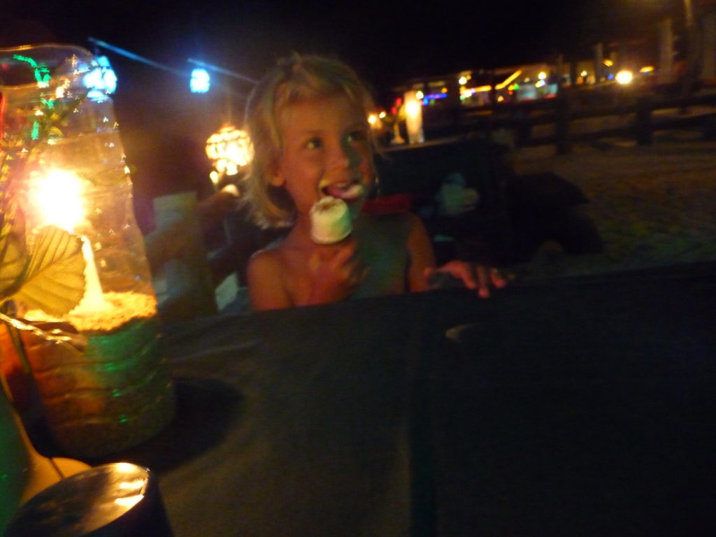 chatounette mange une glace à la table de notre restaurant entre mer et piscine, les pieds dans le sable, la nuit à koh lanta