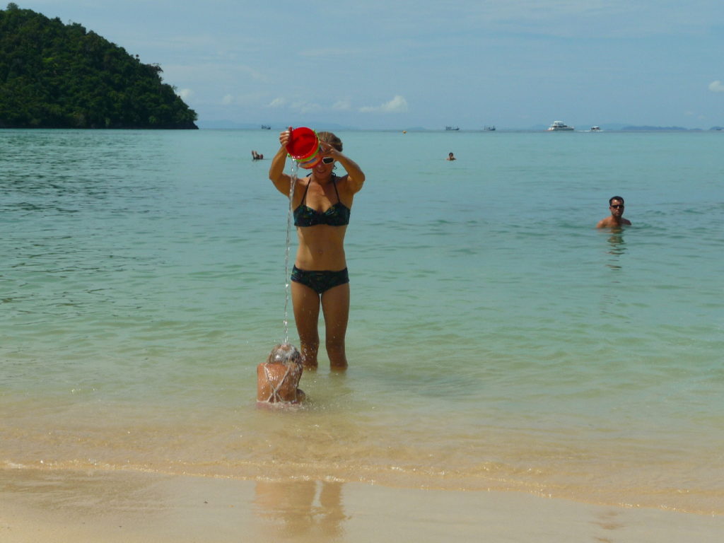chatoune vide son seau d'eau sur la tête de chatounette, plage de koh phi phi
