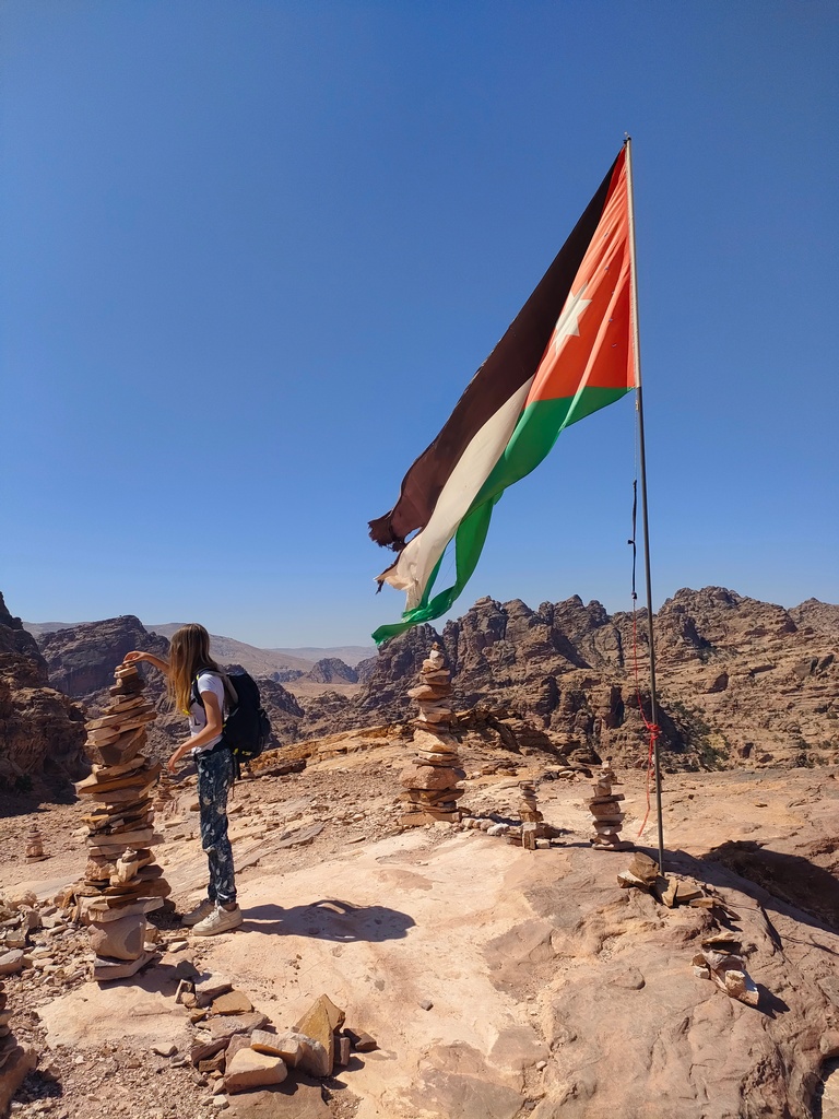 chatounette pose un caillou sur un cairn près du drapeau jordanien